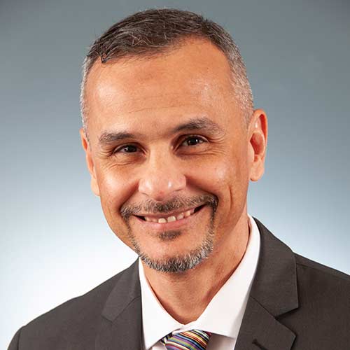 a man wearing a suit and tie smiling at the camera