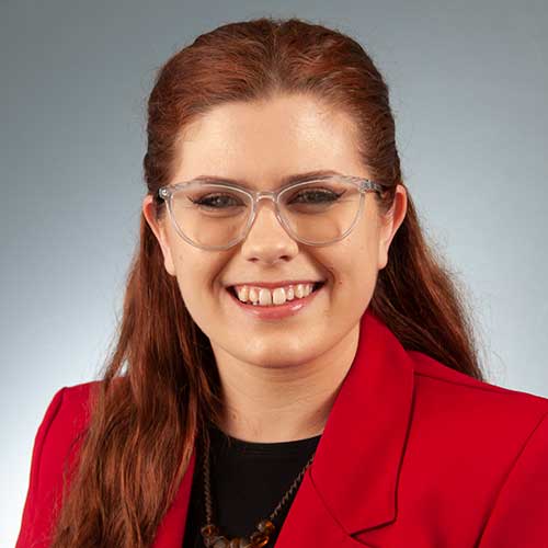 a woman wearing glasses and smiling at the camera