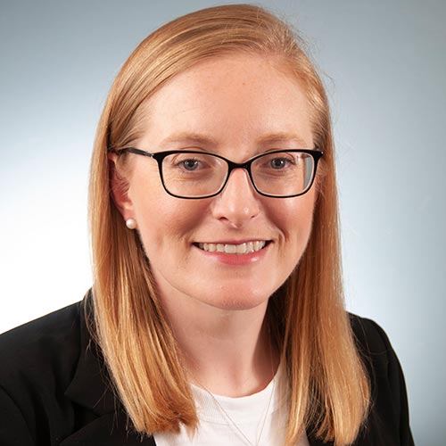 a woman wearing glasses and smiling at the camera