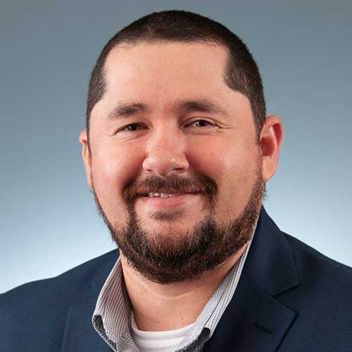 a man wearing a suit and tie smiling at the camera