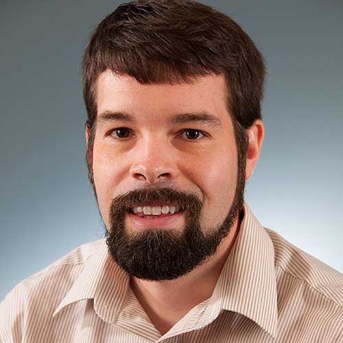 a man wearing a striped shirt and looking at the camera