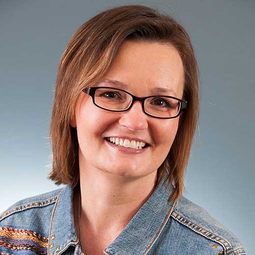 a woman wearing glasses and smiling at the camera