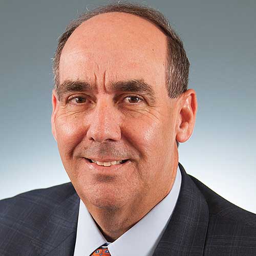 a man wearing a suit and tie smiling at the camera