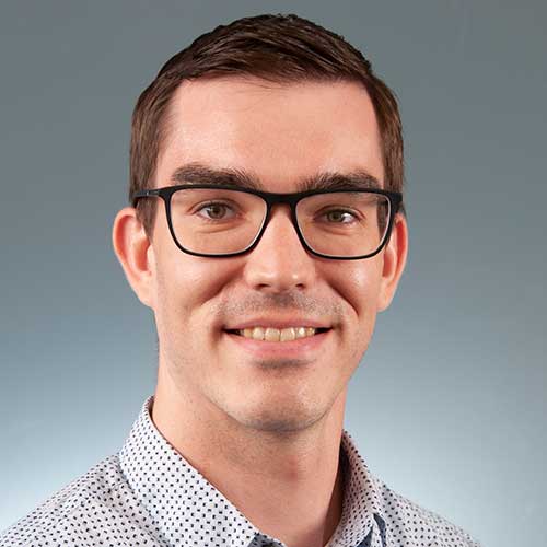 a man wearing glasses and smiling at the camera