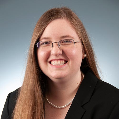 a woman wearing glasses and smiling at the camera