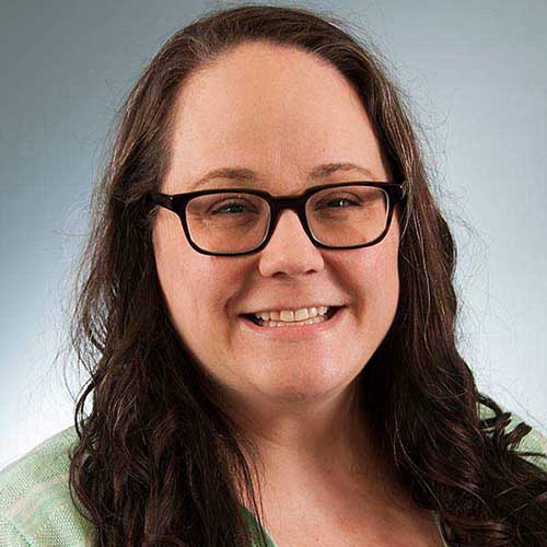 a close up of a person wearing glasses and smiling at the camera