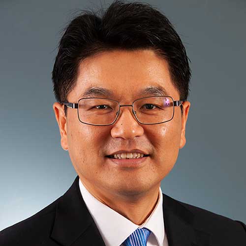 a man wearing a suit and tie smiling at the camera