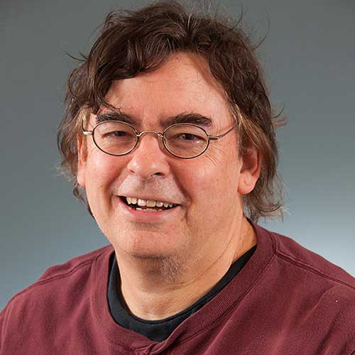 a man wearing glasses and smiling at the camera