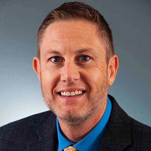 a man wearing a suit and tie smiling at the camera