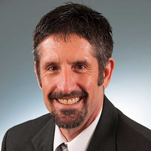 a man wearing a suit and tie smiling and looking at the camera