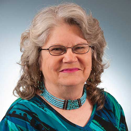 a woman wearing glasses and smiling at the camera