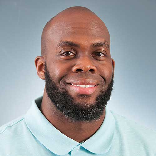 a man wearing a blue shirt and smiling at the camera