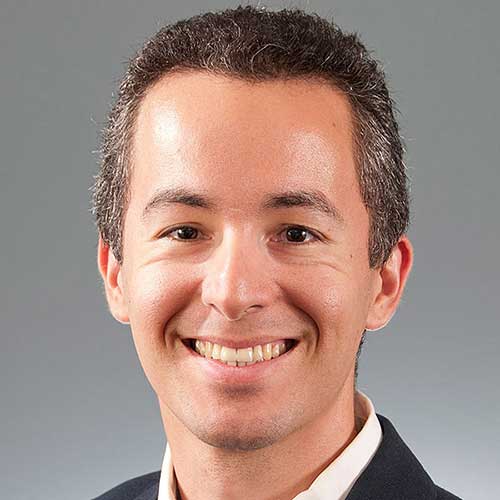 a man wearing a suit and tie smiling at the camera
