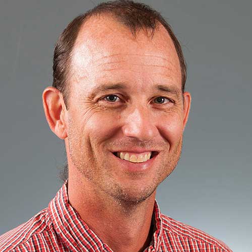 a man wearing a striped shirt and smiling at the camera