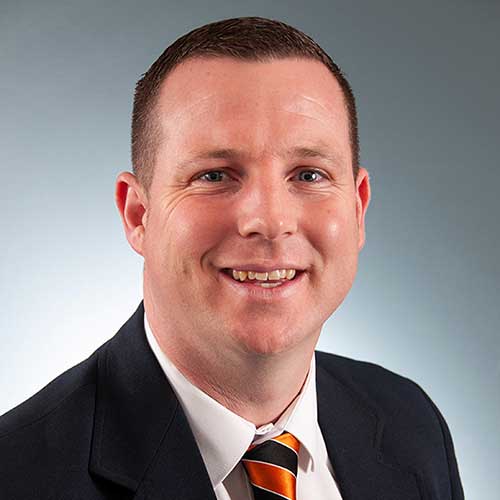 a man wearing a suit and tie smiling at the camera