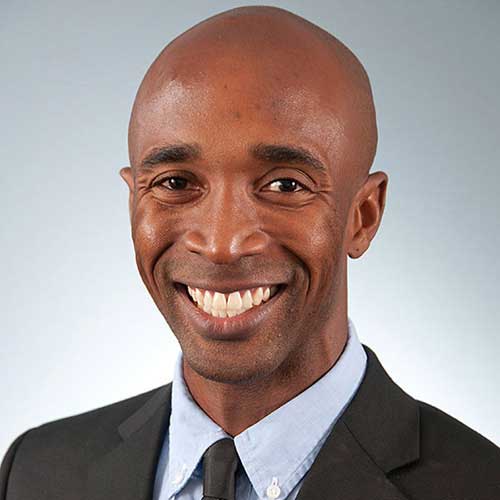 a man wearing a suit and tie smiling at the camera