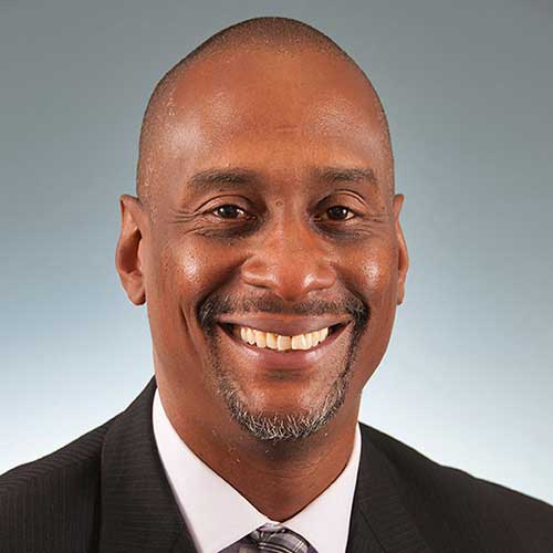 a man wearing a suit and tie smiling at the camera
