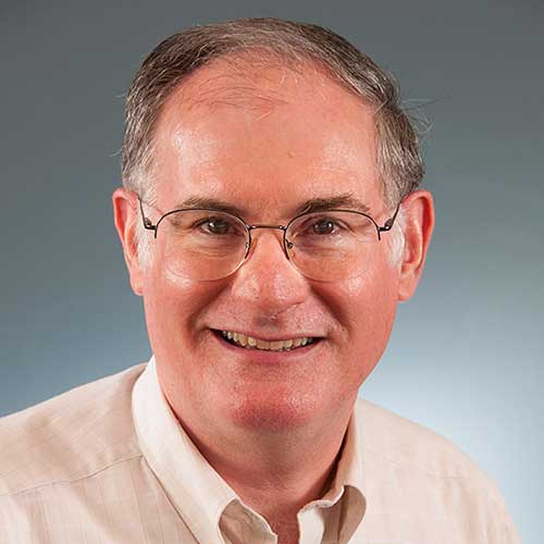 a man wearing glasses and smiling at the camera