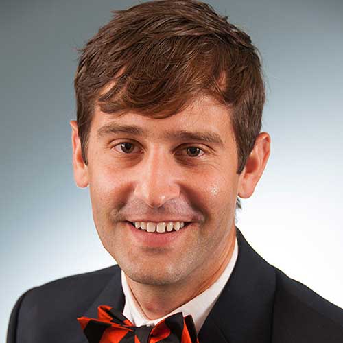 a man wearing a suit and tie smiling at the camera