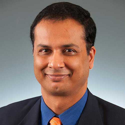a man wearing a suit and tie smiling at the camera