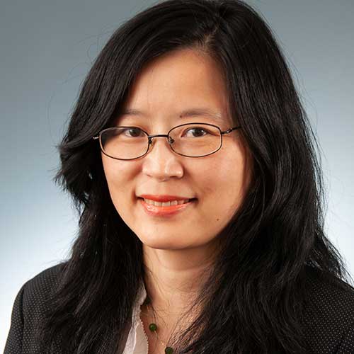 a woman wearing glasses and smiling at the camera