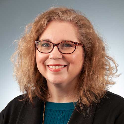 a person wearing glasses and smiling at the camera