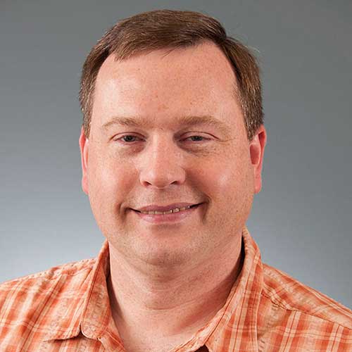 a man wearing glasses and smiling at the camera