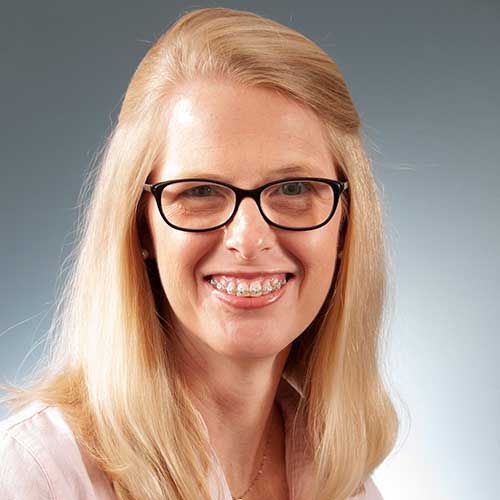 a close up of a woman wearing glasses and smiling at the camera