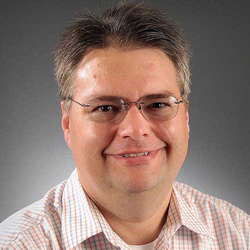 a man wearing glasses and smiling at the camera