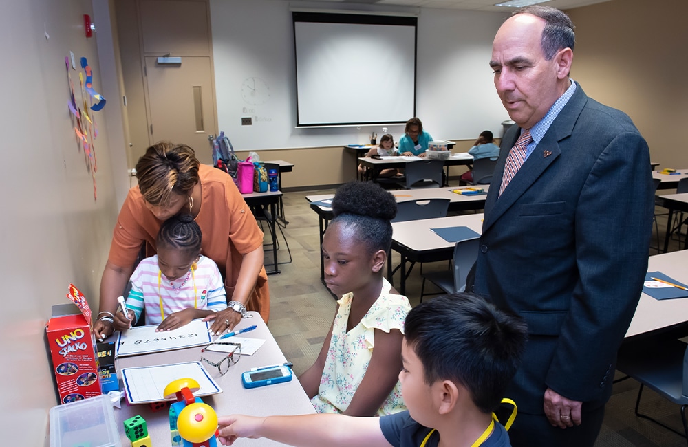 a group of people sitting at a table with a birthday cake
