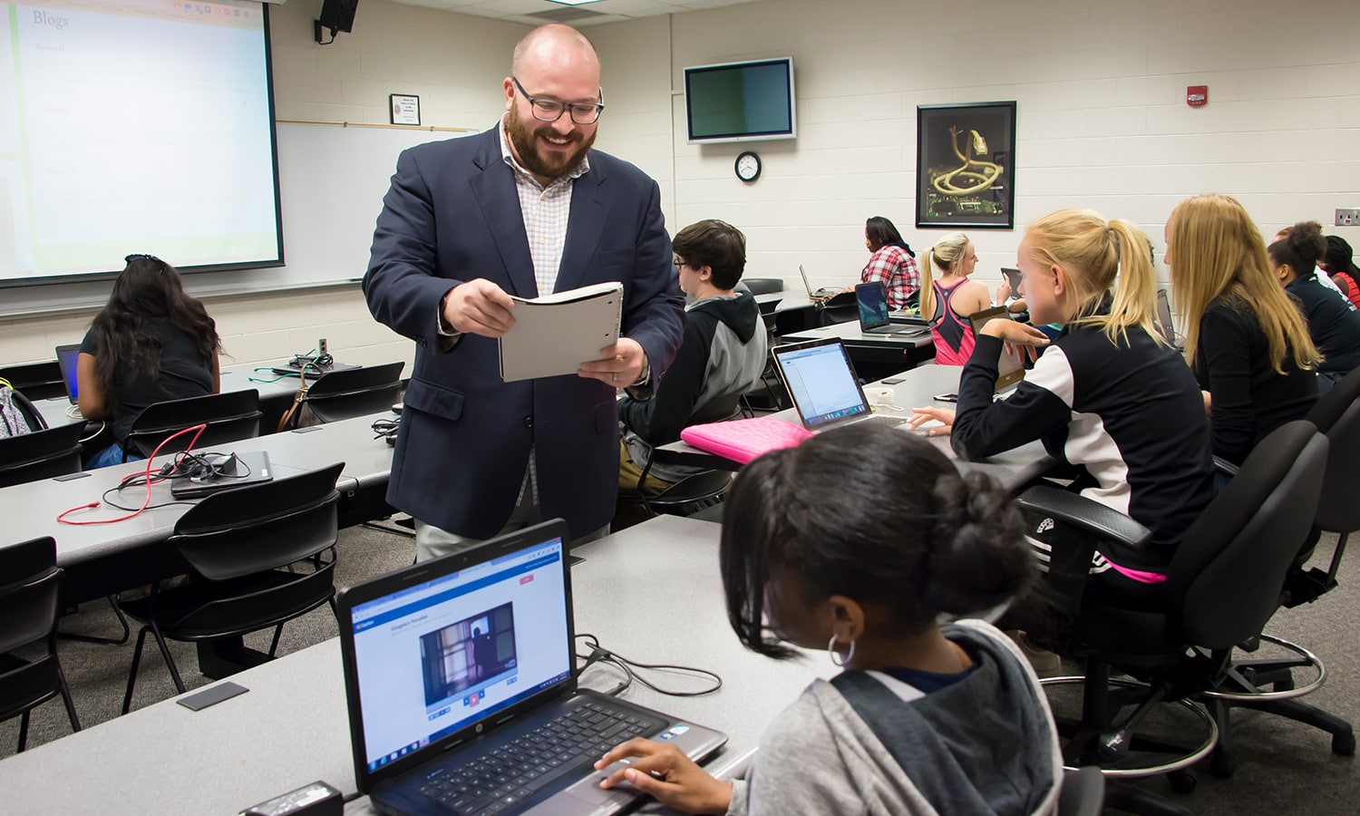 a group of people sitting at a table using a laptop computer a group of people sitting at a table using a laptop computer