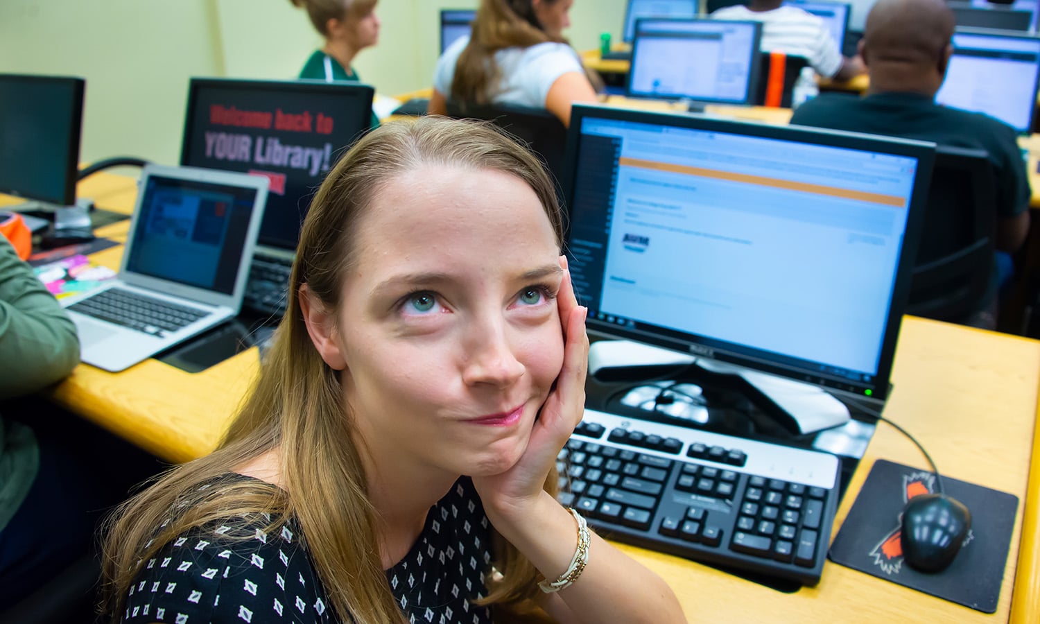 a person sitting at a desk in front of a laptop computer