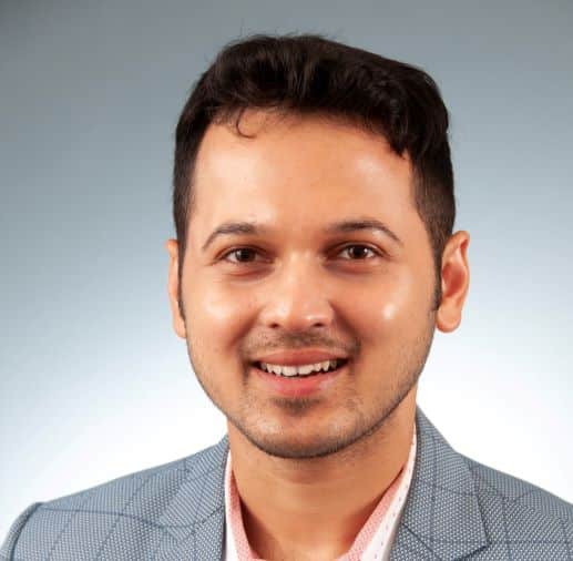 a man wearing a suit and tie smiling at the camera