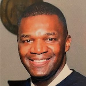 A Man Wearing A Suit And Tie Smiling At The Camera