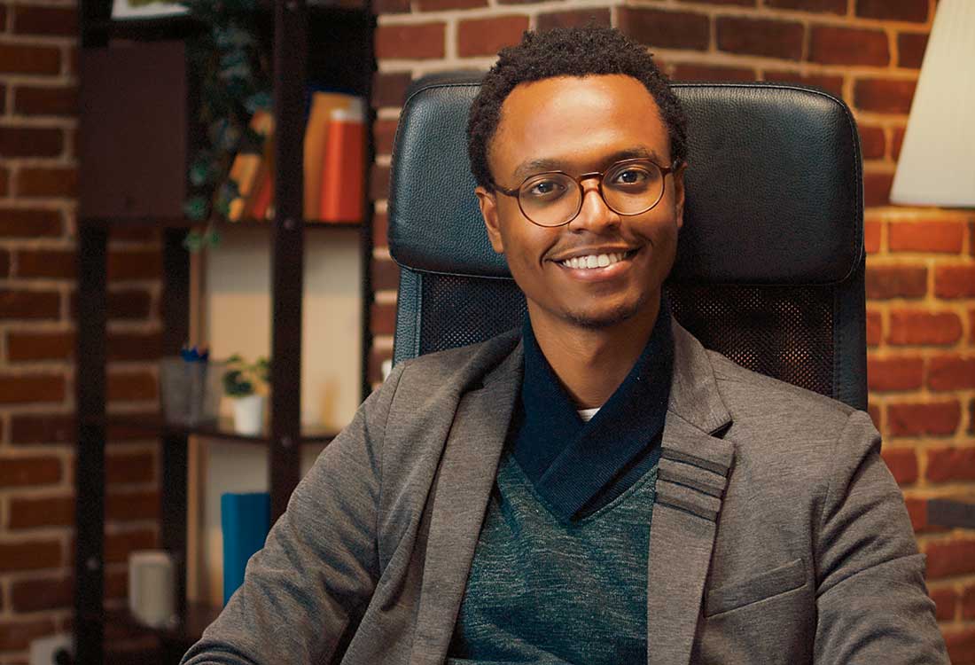 a man wearing a suit and tie in front of a brick building a man wearing a suit and tie in front of a brick building