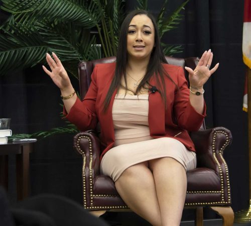 A Woman Sitting On A Bench Posing For The Camera