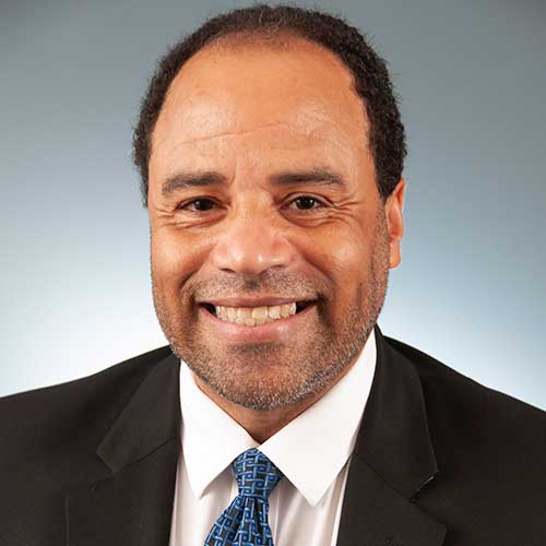 a man wearing a suit and tie smiling at the camera
