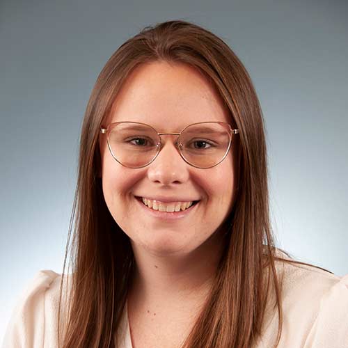 a woman wearing glasses and smiling at the camera