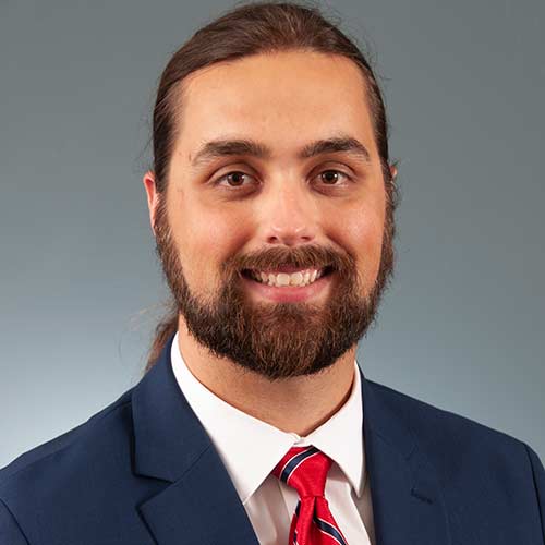 a man wearing a suit and tie smiling at the camera