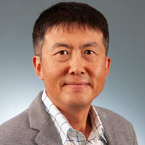 a man wearing a suit and tie smiling at the camera