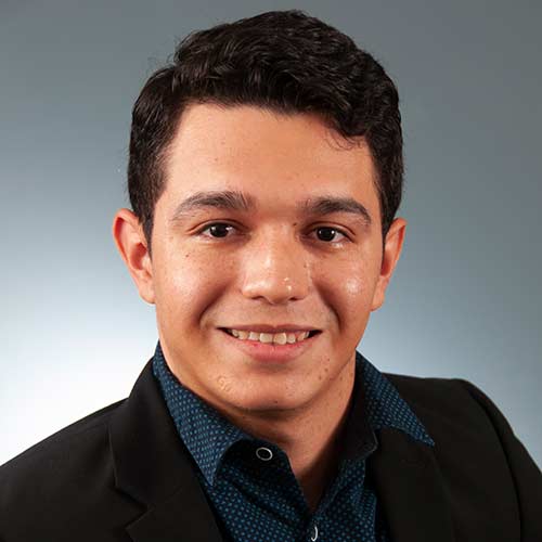 a man wearing a suit and tie smiling at the camera