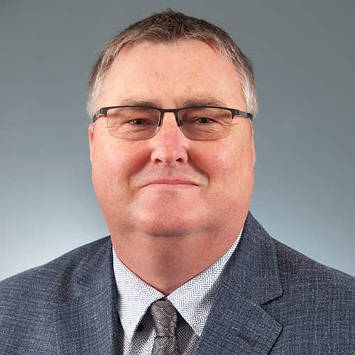 Lee Clark wearing a suit and tie smiling at the camera