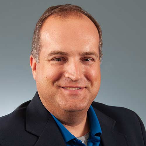 a man wearing a suit and tie smiling at the camera