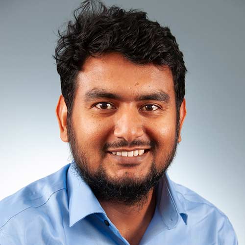 a man wearing a blue shirt and smiling at the camera