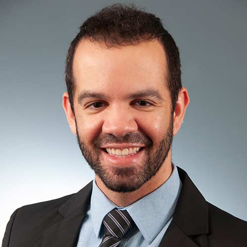 a man wearing a suit and tie smiling at the camera