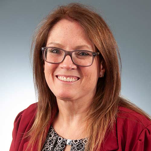 a woman wearing glasses and smiling at the camera