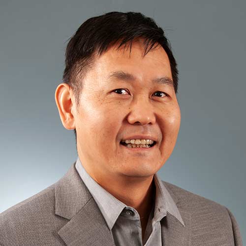 a man wearing a suit and tie smiling at the camera