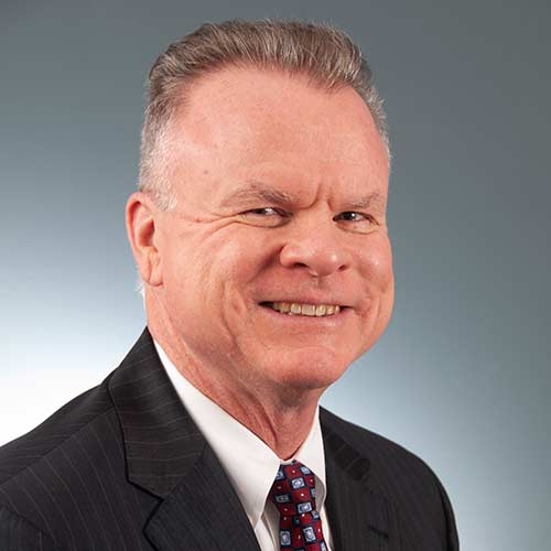 a man wearing a suit and tie smiling at the camera