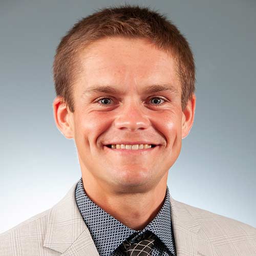 a man wearing a suit and tie smiling at the camera