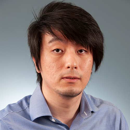 Gong Yoo wearing a suit and tie smiling and looking at the camera